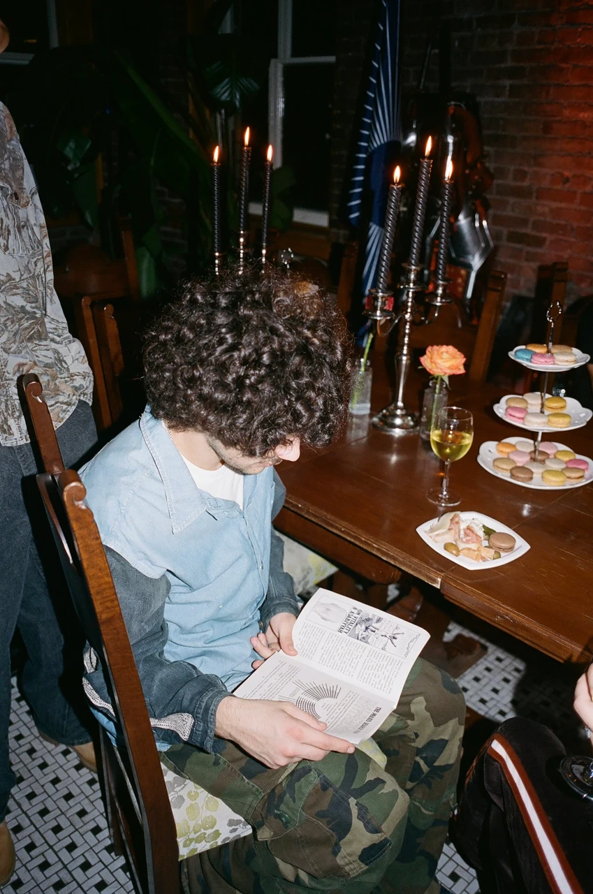 Guest reading a booklet beside a candlelit dining table.